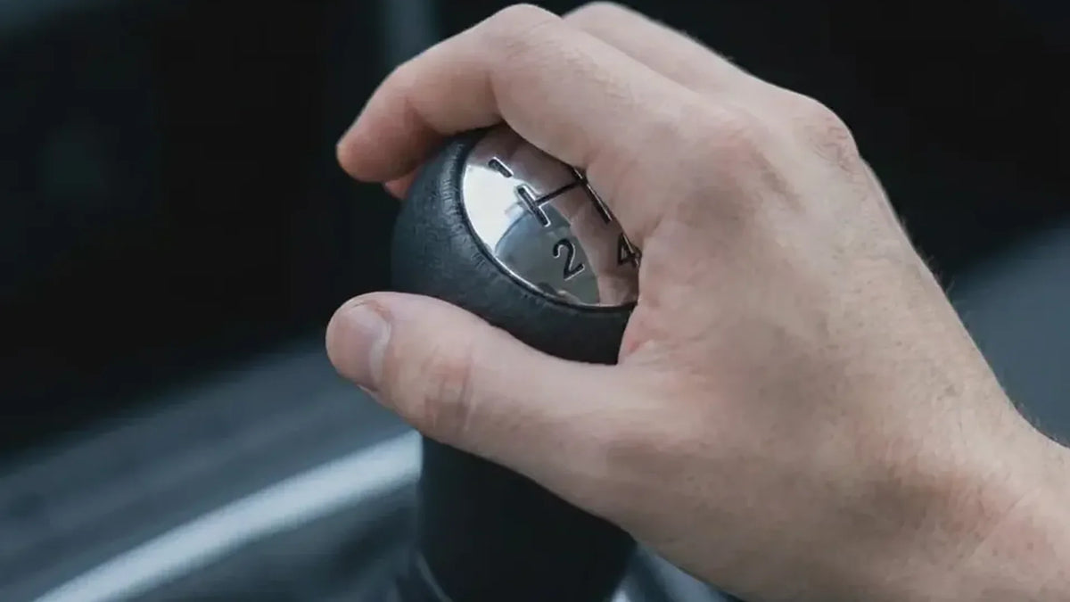 Main du conducteur sur un pommeau de vitesse Dacia Sandero couture noire à schéma 5 vitesses Image