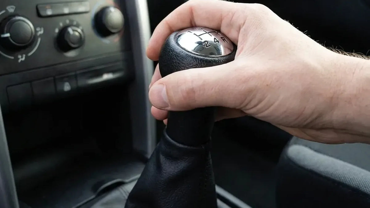 Main du conducteur qui passe une vitesse avec un pommeau de vitesse noir à schéma 5 vitesses monté sur le levier Image
