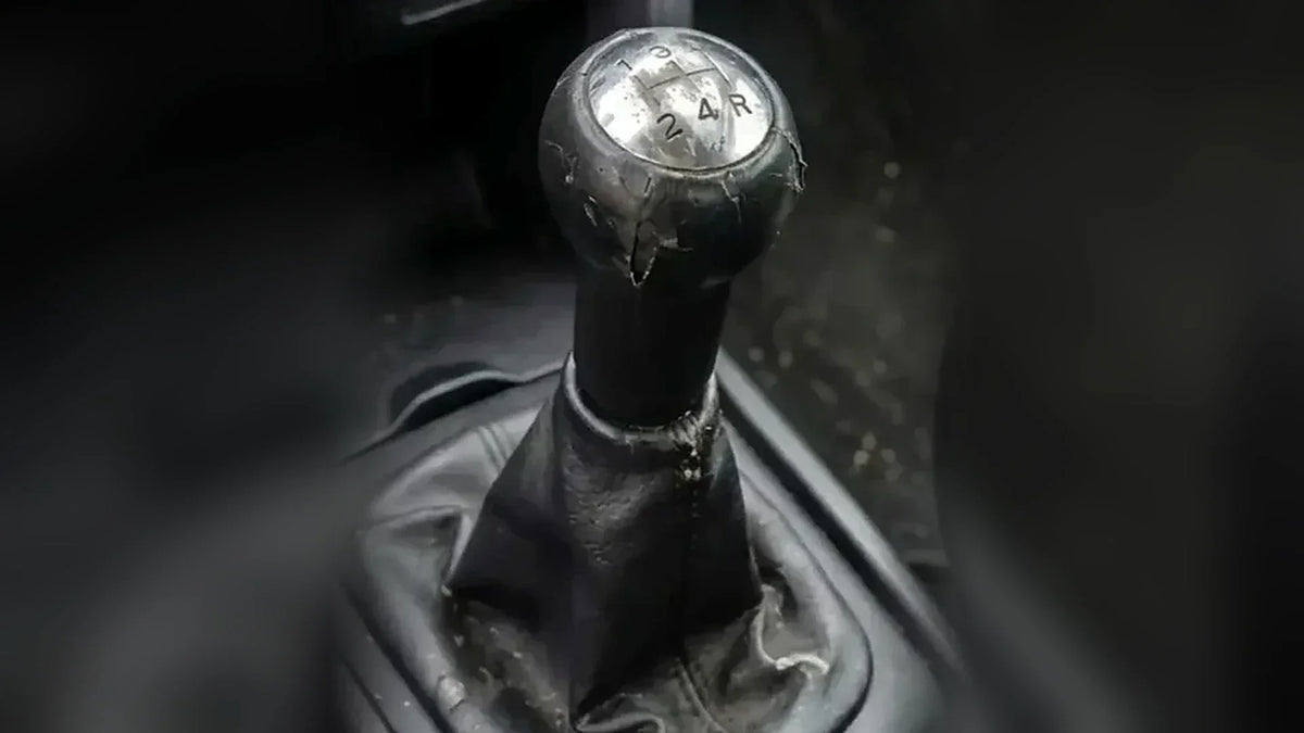 Pommeau de vitesse abîmé dont le revêtement se décolle, sur un levier avec soufflet usé  Image
