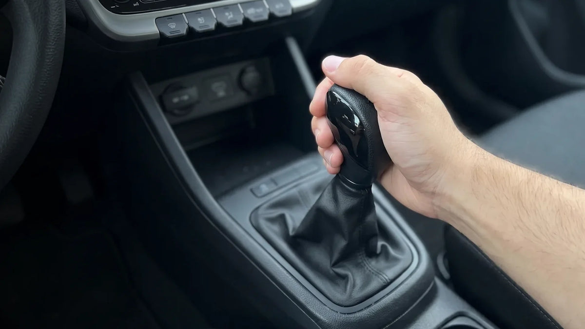 Main qui tient un pommeau de vitesse noir dans l’habitacle d’une voiture