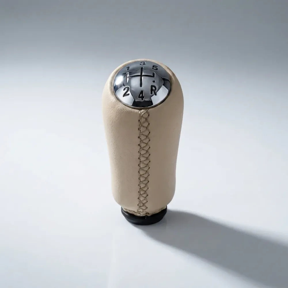 Pommeau de vitesse Clio 3 beige, vue produit isolée avec surpiqûres apparentes et schéma des vitesses gravé